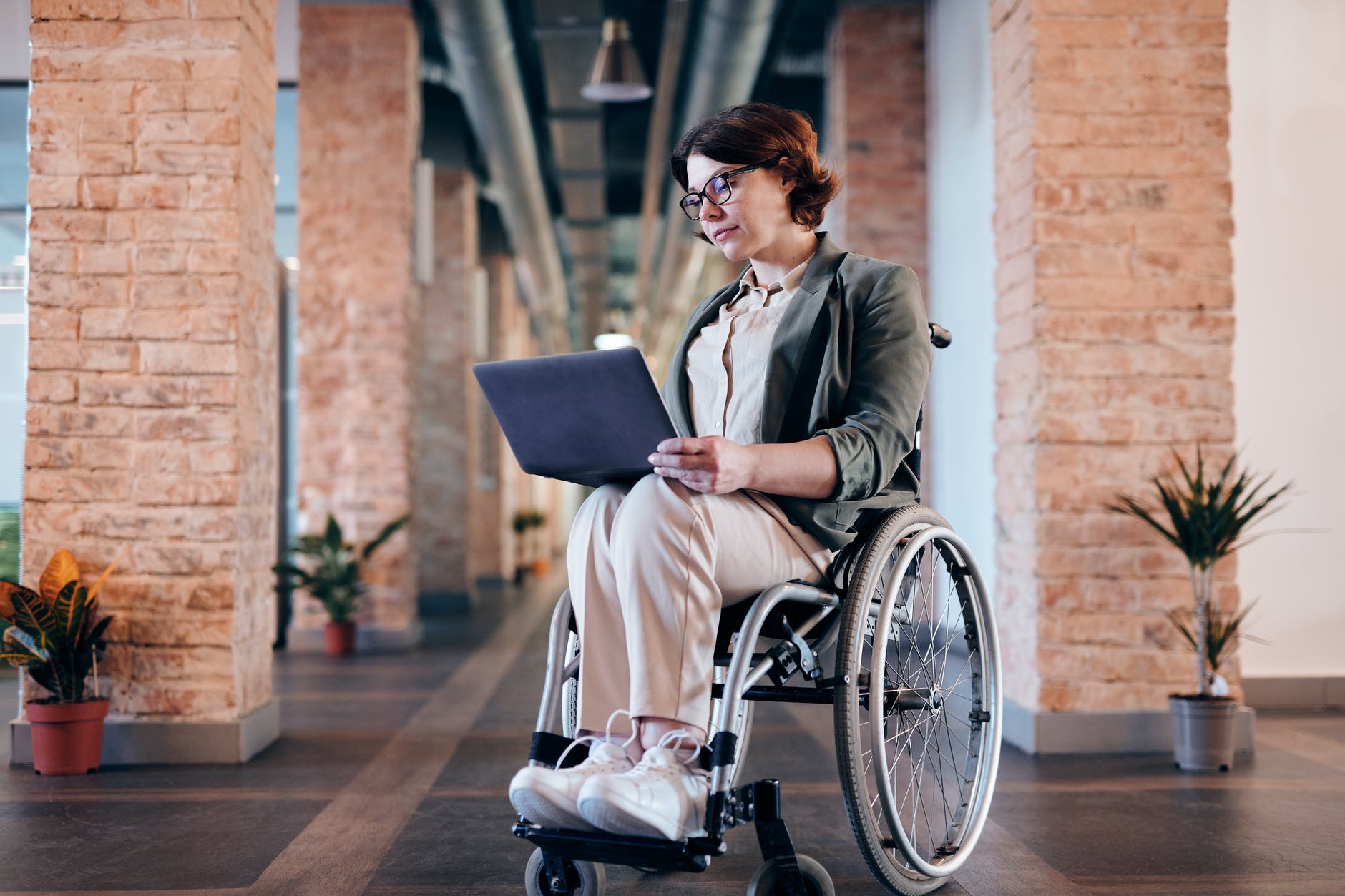 woman sitting on wheelchair while using laptop