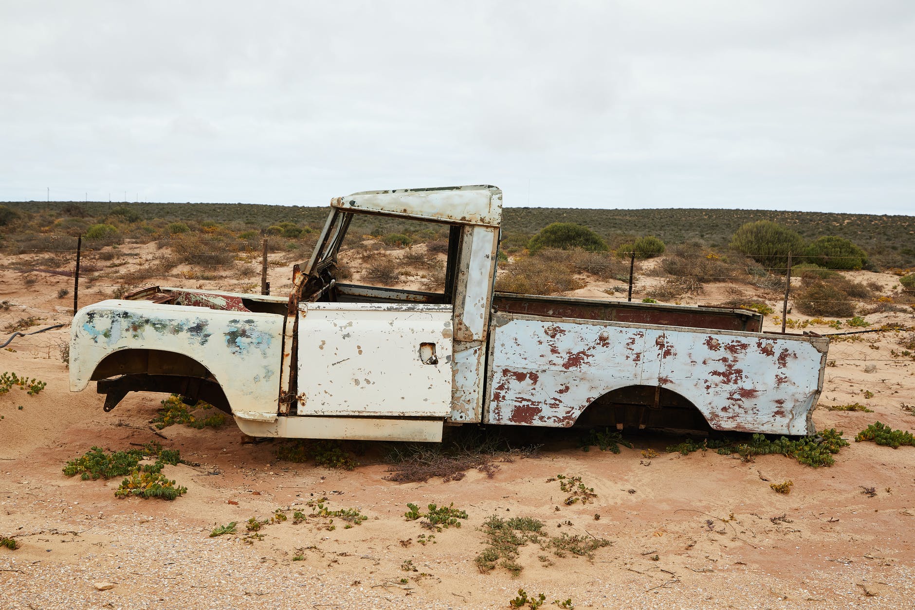 rusty abandoned car near fence in desert